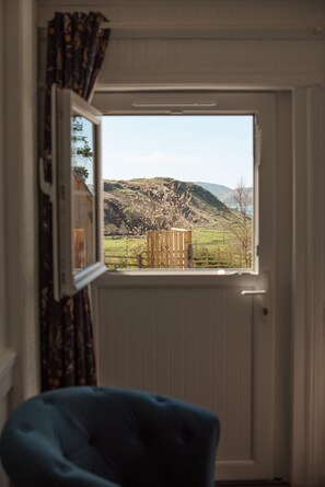 Ein Zimmer mit Blick aus dem Fenster auf eine ländliche Landschaft, einem Holzzaun und einem Stuhl.