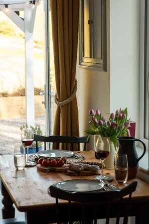 A dining table set with plates, glasses, and a pitcher, with chairs around it. - Charming one bed cottage (Oban)