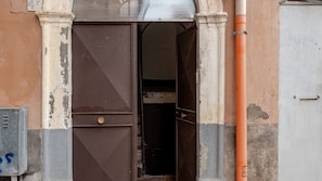 Una puerta entreabierta con un picaporte metálico, un espacio interior visible y una caja de servicios a la izquierda.