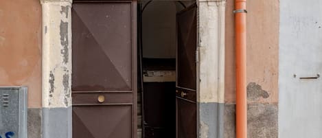 Una puerta entreabierta con un picaporte metálico, un espacio interior visible y una caja de servicios a la izquierda.
