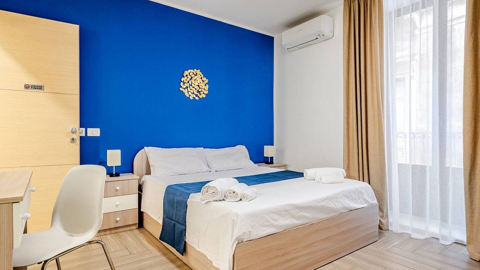 Een hotelkamer met een bed, nachtkastjes, een bureau en een airconditioner.