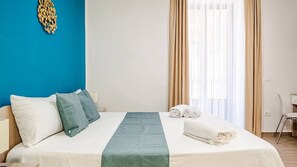 A hotel room with a bed, pillows, a folded towel, a nightstand, and a window with curtains. - 4min Central Station 3 Room & 3 private bathroom (Catania)