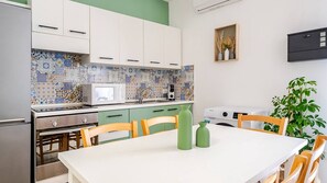 A kitchen with white cabinets, a microwave, a sink, and a dining table with chairs. - 4min Central Station 3 Room & 3 private bathroom (Catania)