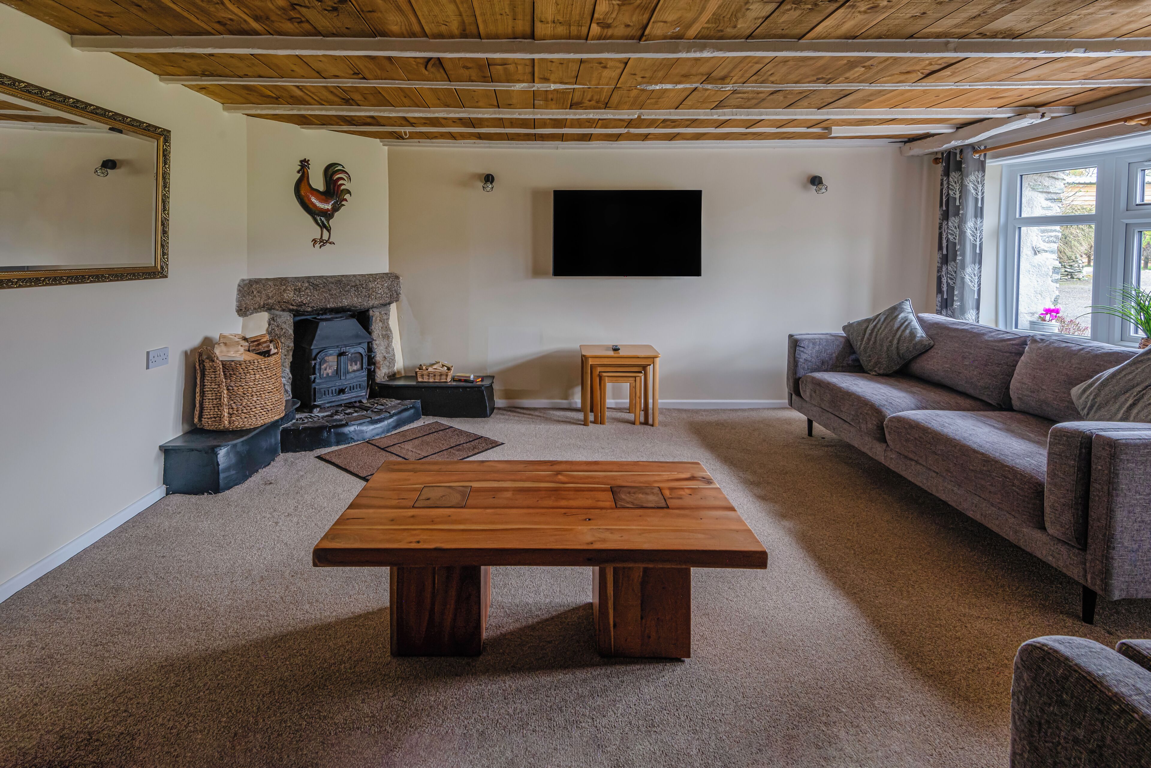 A living room with a wooden ceiling, a fireplace, a sofa, a coffee table, and a television.
