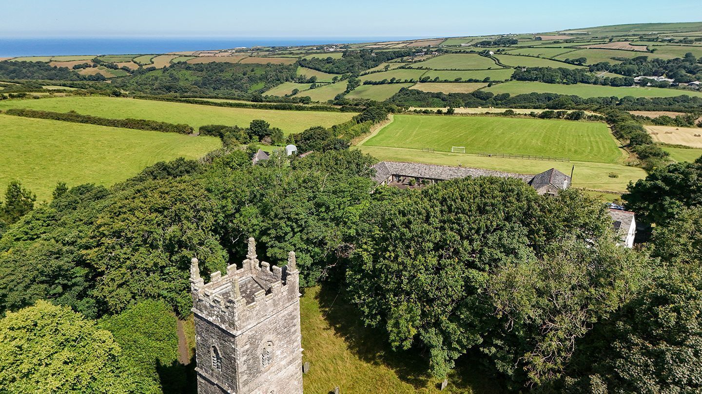 Un château doté d’une tour, entouré de champs verdoyants et offrant une vue sur la mer.