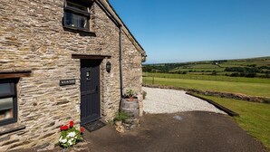 A stone building with a black door, a window, and a sign that reads 'WEAVERS.' - Courtyard Farm Cottages (Boscastle)
