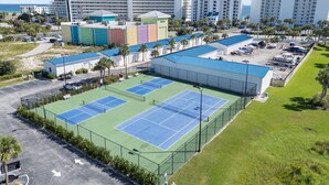 Un hotel de varios pisos con un amplio complejo de canchas de tenis.