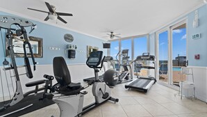 Un gimnasio con equipo de ejercicio, una cinta de correr y vistas al océano.