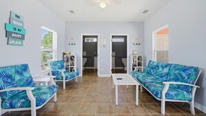 A room with two white sofas, a small table, and a ceiling fan. There are two doors leading to a bathroom and a closet. - Rookery III 6005 - Peach and Quiet (Gulf Shores)