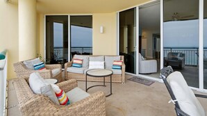 A balcony with wicker furniture, a small table, and a chair. - Beach Colony East 7B (Pensacola)
