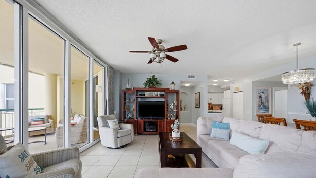 A spacious living room with a large TV, comfortable seating, and a ceiling fan. - Beach Colony East 7B (Pensacola)