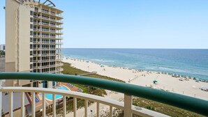 A high-rise hotel with multiple balconies overlooking a beach with sun loungers and umbrellas. - Beach Colony East 7B (Pensacola)