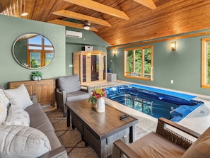 A spa area with a hot tub, wooden ceiling beams, a mirror, and a view of the outdoors. - 5BR Mountain Retreat | Indoor Spa + Sauna + Views (Clyde)