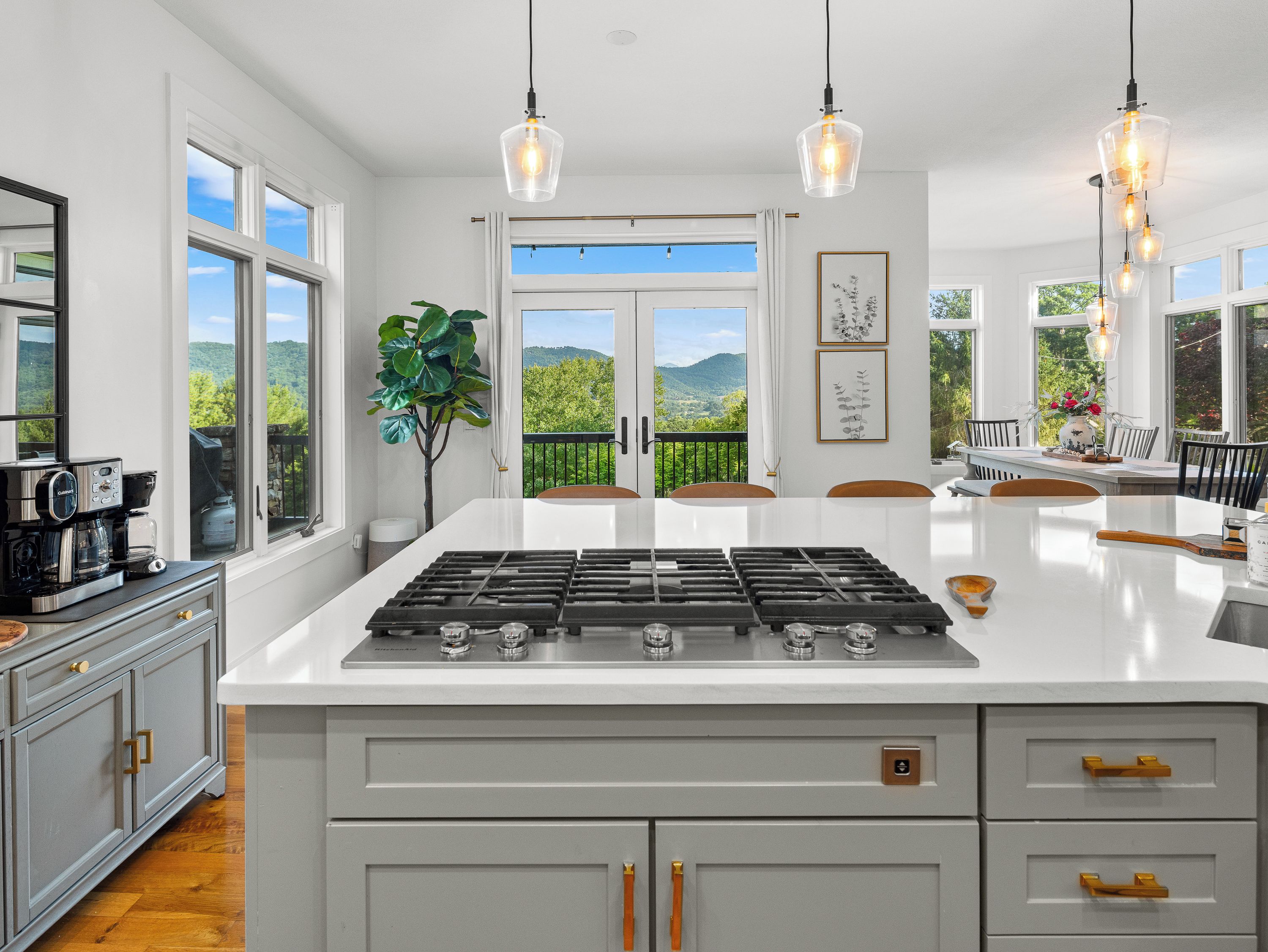 Una cocina moderna con una isla central, ventanas amplias y vistas al verdor.