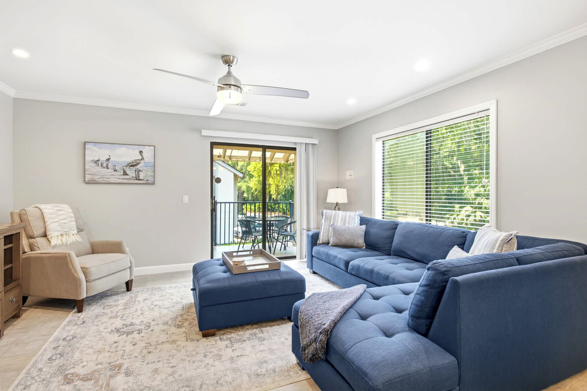 A living room with a sofa, ottoman, and a ceiling fan.