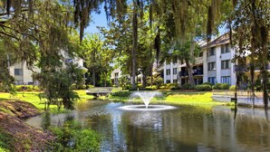 A serene pond with a fountain, surrounded by lush greenery and multi-story buildings. - Family Beach Retreat Near Coligny Beach (Hilton Head Island)