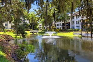 A serene pond with a fountain, surrounded by lush greenery and multi-story buildings. - Family Beach Retreat Near Coligny Beach (Hilton Head Island)