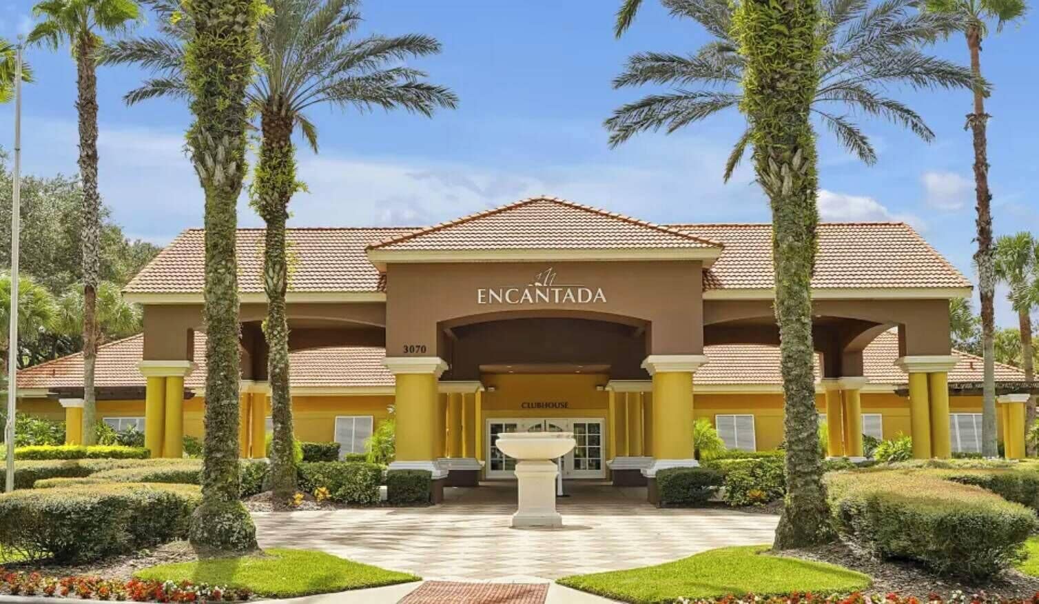 Step into a welcoming facade embraced by lush palm trees, where warm yellow tones invite relaxation. The charming entrance, framed by manicured landscaping, creates a refreshing and elegant atmosphere for all guests.