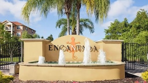 Welcome to a peaceful entrance with a charming fountain and swaying palm trees. The warm colors of the signage and landscape create an inviting first impression, setting the perfect tone for your stay. - 3BR house with private pool in kissimmee (Kissimmee)