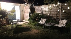 An outdoor patio with a table and two chairs, a brick wall, and string lights.