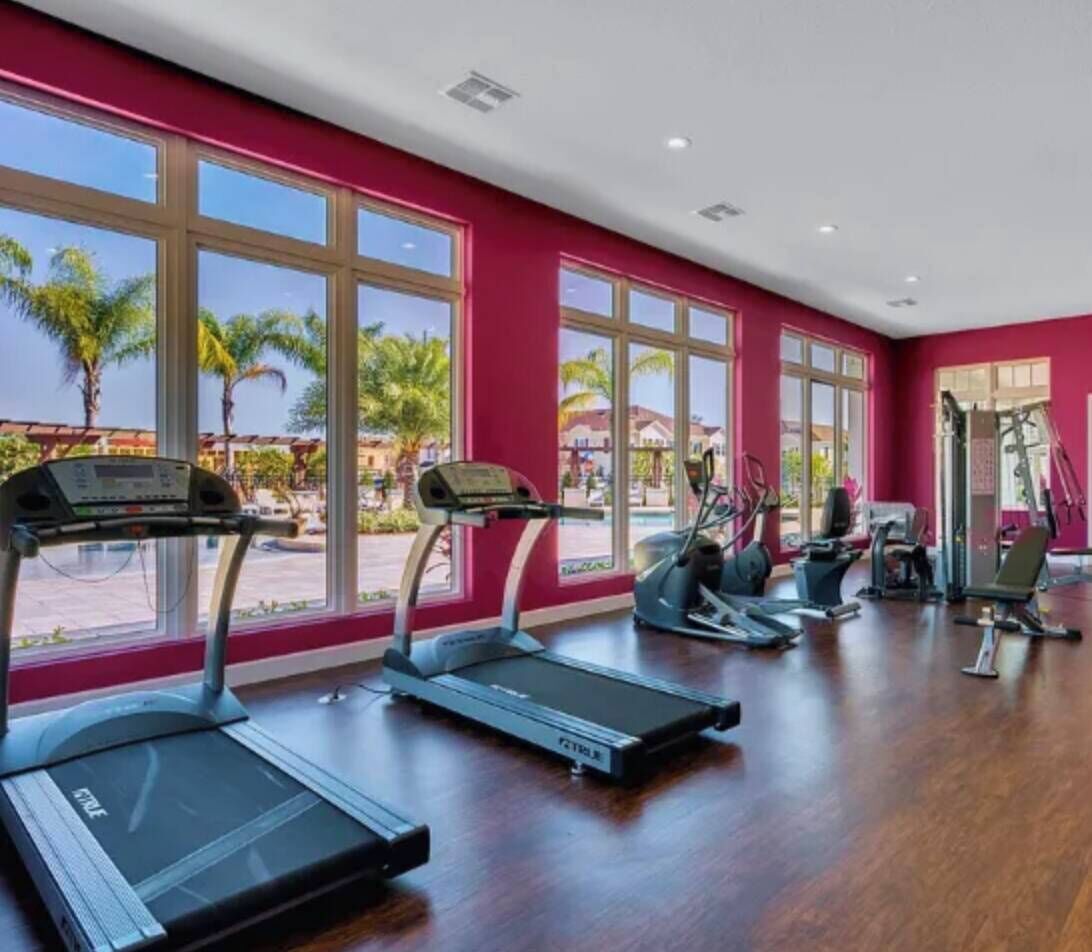 Our lively fitness room, with bright red walls and large windows, invites you to enjoy natural light and views of palm trees while you stay motivated with our modern equipment, including sleek treadmills and ellipticals for an.