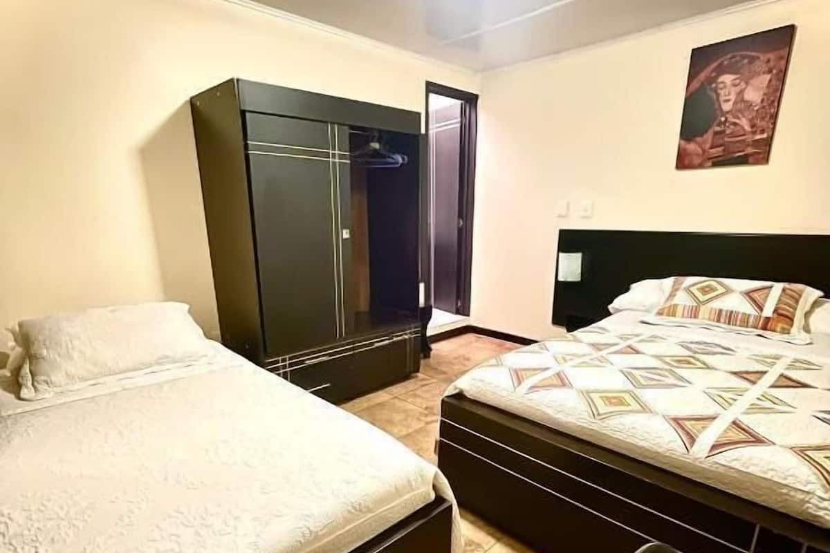 Un dormitorio con dos camas, un armario y un escritorio.