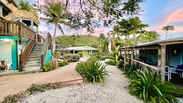 Resort com uma escadaria de madeira, área de estar coberta ao ar livre e um caminho que leva a um edifício com telhado verde.