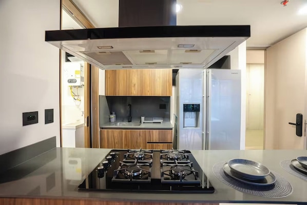 Uma cozinha moderna com fogão a gás, forno embutido e geladeira.