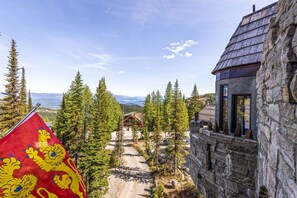A stone building with a wooden roof, a flag with lion designs, and a mountain view.