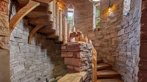 Ein Innenraum mit Steinwänden, einer Holztreppe und einem Holnänder.