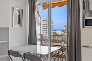 A balcony with a table and chairs, a TV, and a view of the sea and buildings. - 'Las Naciones' Studio with Sea Views, Wi-Fi, and Air Conditioning (Benalmádena)
