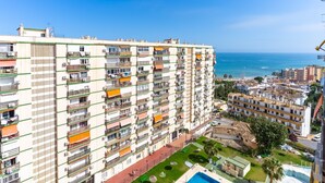 Un edificio alto con varios balcones, una piscina y vistas al mar.