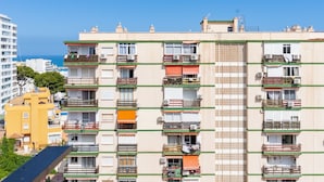 Un edificio residencial de varios pisos con balcones, unidades de aire acondicionado y una fachada estampada.
