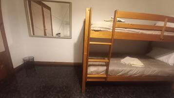 A bunk bed with a ladder, a mirror on the wall, and a small trash bin.