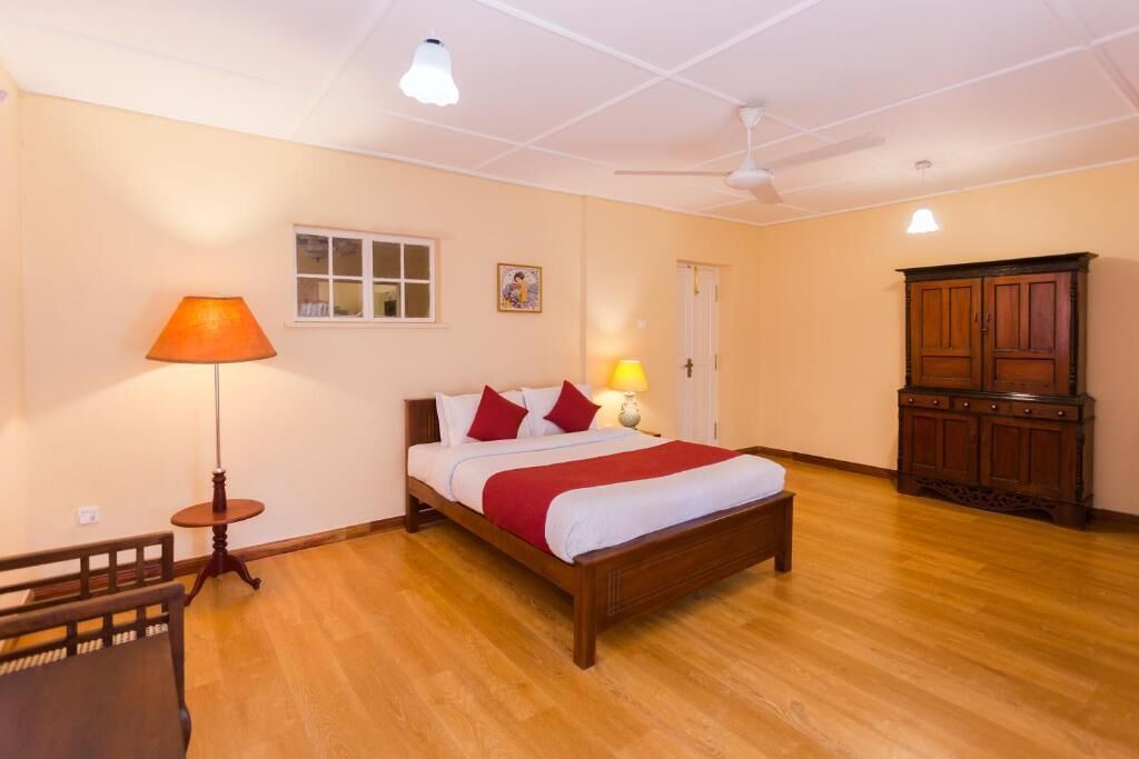 Een slaapkamer met een houten bed, een nachtkastje, een lamp, een garderobe en een plafondventilator.