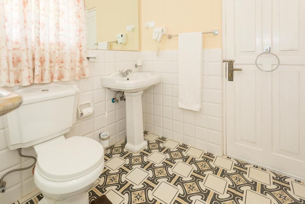 Een badkamer met toilet, wastafel en vloertegels met een patroon.
