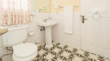 Een badkamer met toilet, wastafel en vloertegels met een patroon.