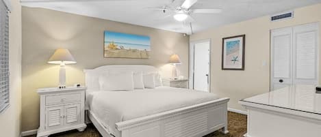 A bedroom with a bed, two bedside tables, a ceiling fan, and a painting on the wall.