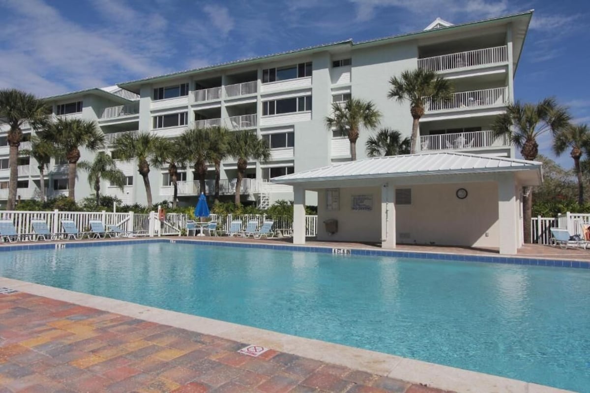 Un hotel con piscina, varios balcones y palmeras.