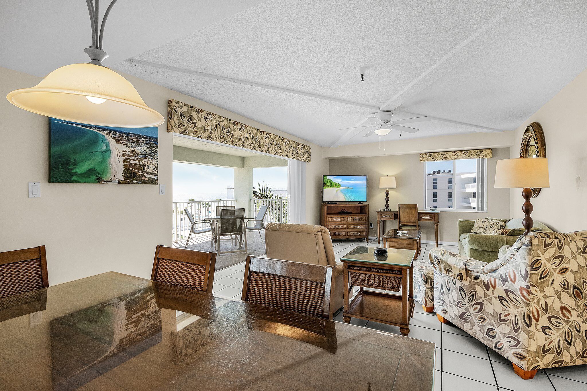 A spacious living room with a dining area, a sofa, a TV, and a balcony with a view.