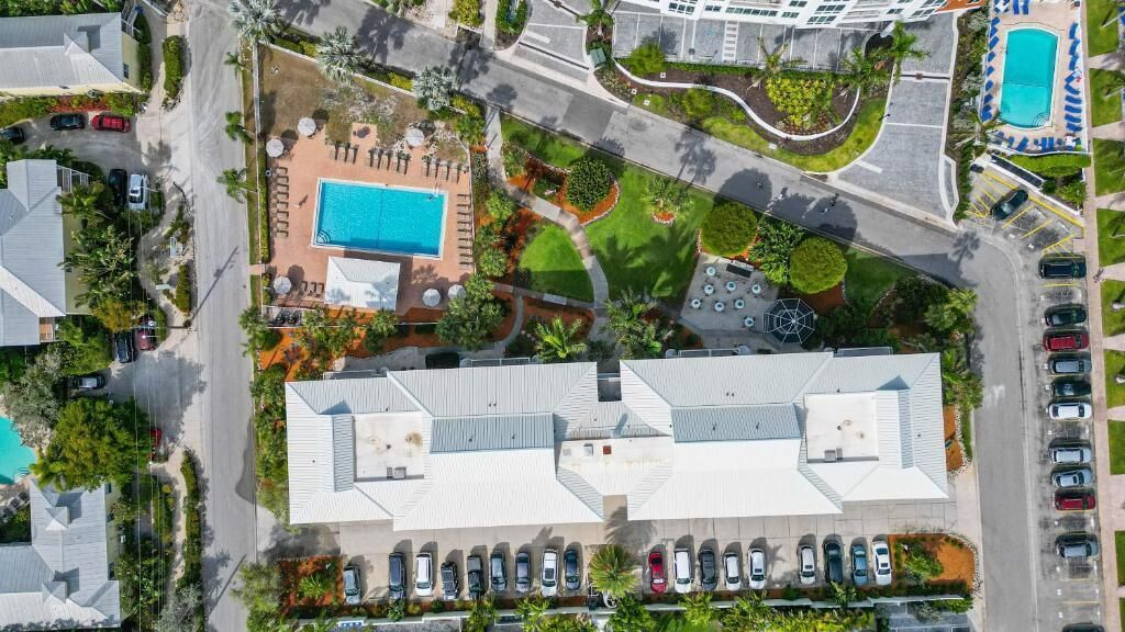 An aerial view of a hotel with a swimming pool, parking lot, and landscaped areas.