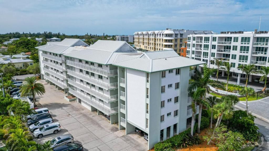 A multi-story hotel with balconies, a parking lot, and surrounding greenery.