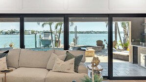 Ein modernes Wohnzimmer mit großem Fenster und Blick auf Pool und Wasser.