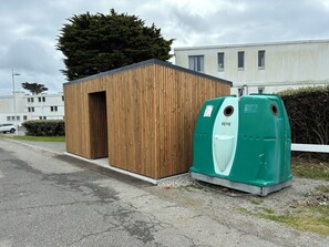 Ein kleines Holzgebäude mit einem grünen Wasserspender davor.