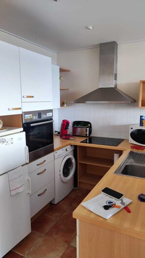 Eine kompakte Küche mit Waschmaschine, Toaster und Mikrowelle.