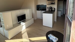Een moderne keuken met witte kasten, een inbouwoven en een koffieapparaat.