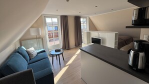 Een modern appartement met een zithoek, kitchenette en balkon.