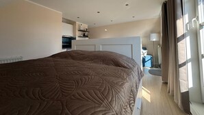 Een moderne hotelkamer met een groot bed, een kitchenette en uitzicht op de stad.
