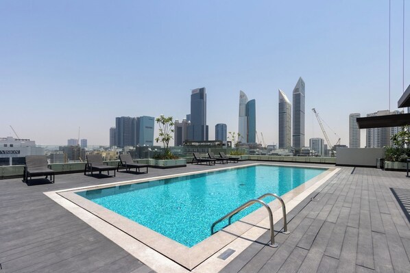 A rooftop pool with lounge chairs and a city skyline view. - Modern 1B | Rooftop Pool | DIFC and DowntownAccess (Dubai)