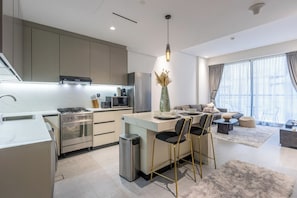 A modern kitchen with a central island, stainless steel appliances, and a dining area with bar stools. - Modern 1B | Rooftop Pool | DIFC and DowntownAccess (Dubai)